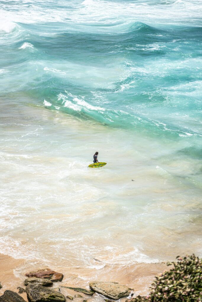 A lone surfer with a green surfboard on Bondi Beach's vibrant waves.